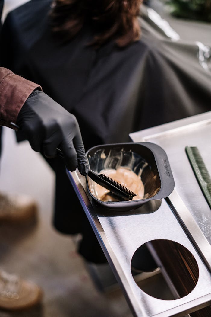 Home Stylist preparing hair dye at a salon with professional tools ready for application.